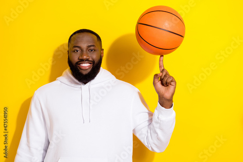 Photo of cool young beard man spin ball wear white sportscloth isolated on yellow color background
