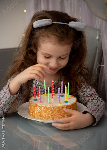 A cute little girl with the cake. House. Birthday. Atmosphere.