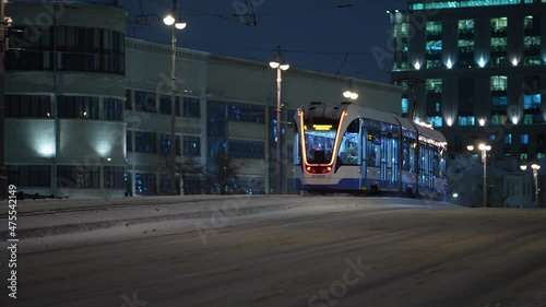 Winter, nighttime cityscape modern tram rides across the bridge in winter