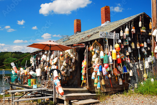 A lobster shack in Maine is decorated with numerous lobster buoys and a sign advising their food is fresh off the boat photo