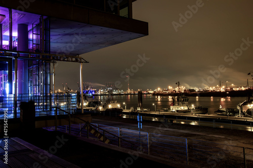 Blick auf den Hamburger Hafen bei Nacht und ein Gebäude mit Glasfront und lila Licht