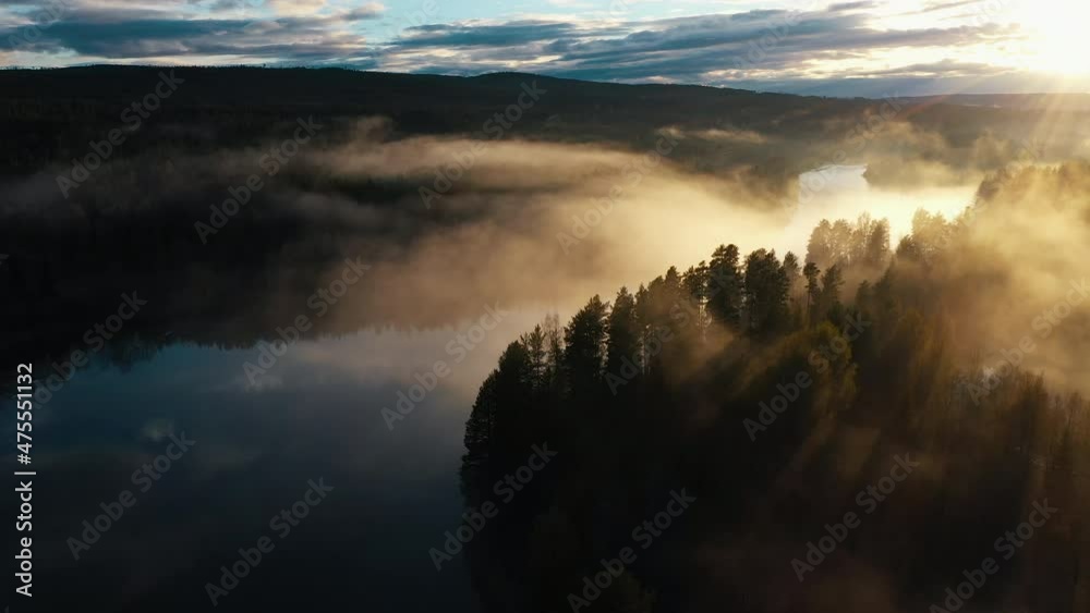 An aerial shot of a majestic sunset over a river running through a pine tree forest