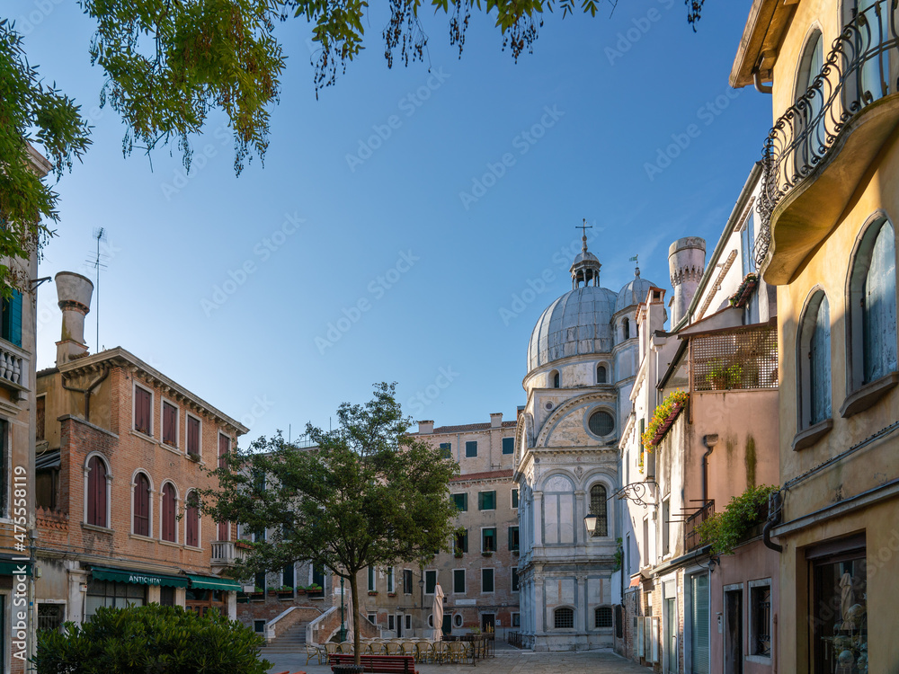 Romantic little square in Venice in morning with no people, marble church in background 
