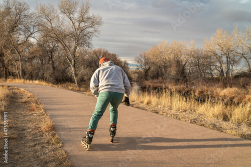 senior male  is inline skating on a paved bike trail along Poudre River in Fort Collins, Colorado, fall or winter scenery photo