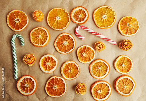 Dried orange slices, roses made of tangerine peel and candy canes on craft paper. Christmas concept background