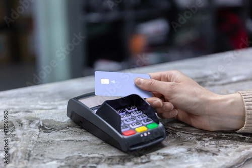 Obraz na płótnie Hand of customer paying with contactless credit card with NFC technology. Bartender with a credit card reader machine at bar counter with female holding credit card. Focus on hands. w salonie