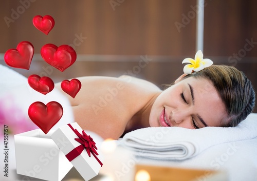 Heart icons over a gift box against against woman receiving a massage at a spa