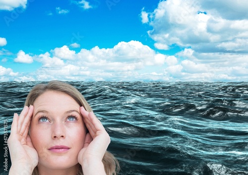 Composite image of caucasian woman looking upwards against against blue sky over sea waves