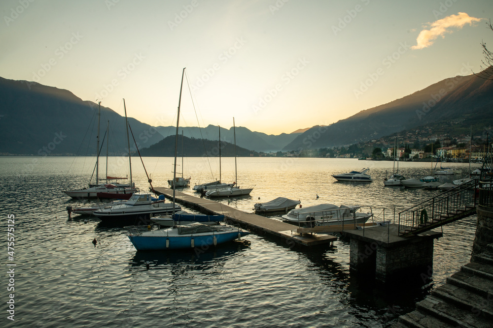 pier and yacht mooring on it as sailing boats .. Sunset on Lake Como / Christmas holidays