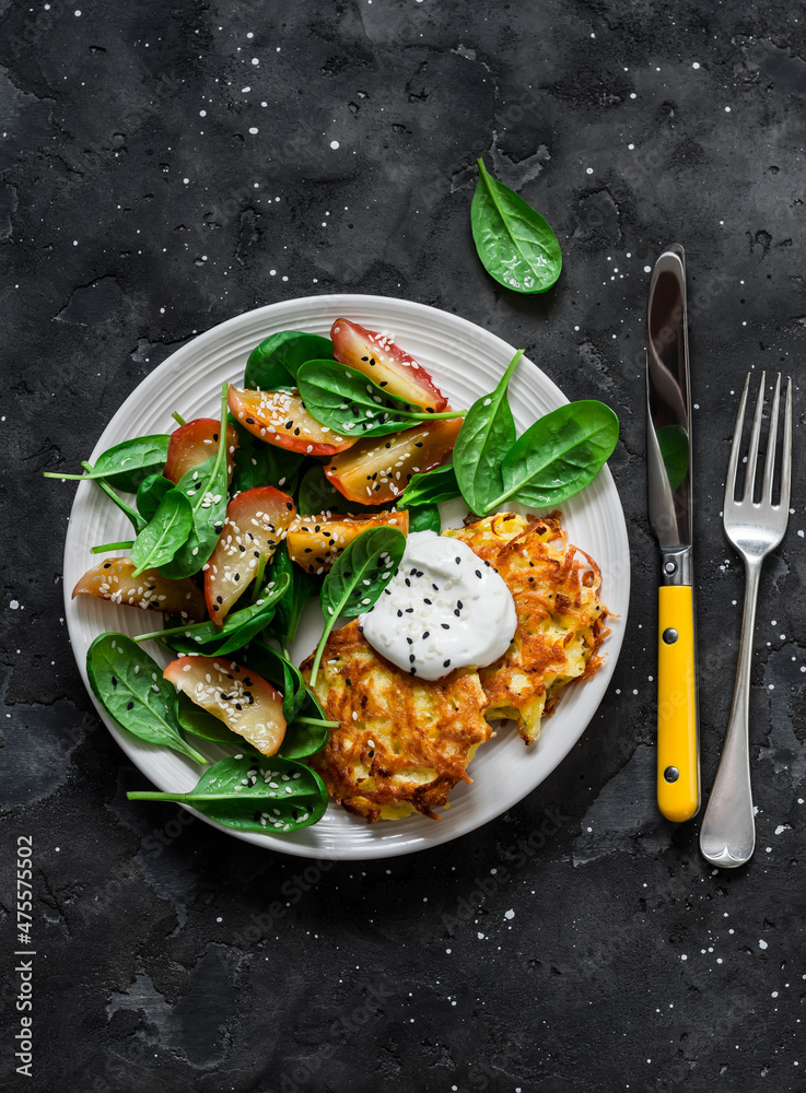 Potato latkes with baked apples, spinach salad on a dark background, top view. Delicious breakfast, snack, vegetarian lunch Potato latkes with baked apples, spinach salad on a dark background, top view. Delicious breakfast, snack, vegetarian lunch