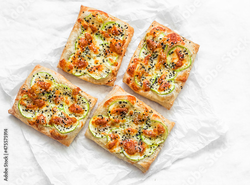 Mini pizza with zucchini, mozzarella and sesame on a light background, top view. Delicious snack, snack, tapas