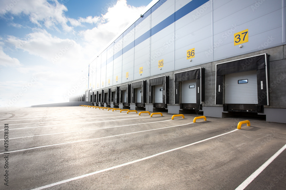 Wall of a huge distribution warehouse with row of loading gates - obrazy, fototapety, plakaty 