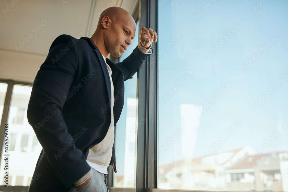 Below view of African American businessman looks through the window from his office. Below view of African American businessman looks through the window from his office.