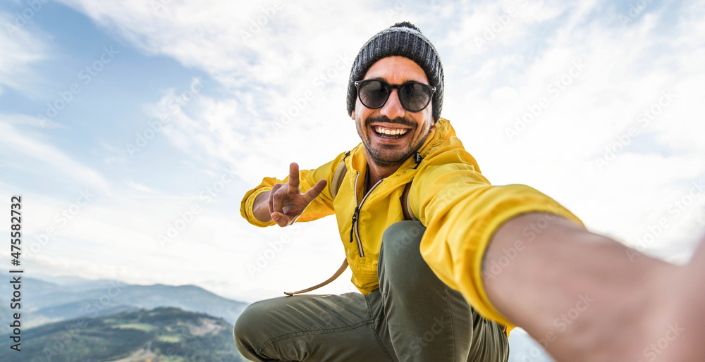 Young hiker man taking selfie portrait on the top of mountain - Happy guy smiling at camera - Hiking and climbing cliff - obrazy, fototapety, plakaty 