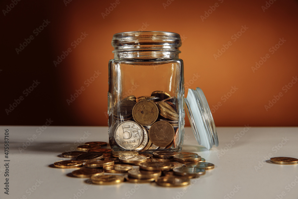 Glass jar with coins on a table. Savings concept Glass jar with coins on a table. Savings concept