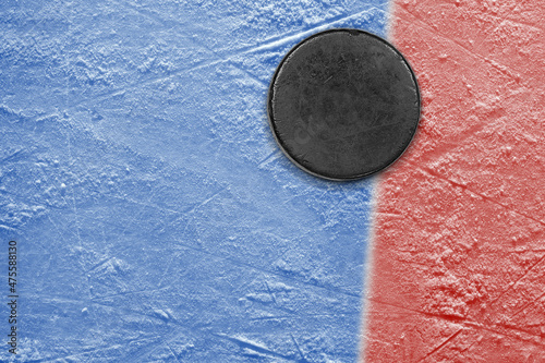 Hockey puck on blue ice with red stripe