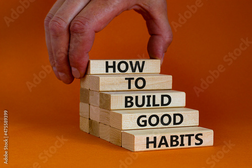 Build good habits symbol. Wooden blocks on beautiful orange background, copy space. Words 'How to build good habits'. Businessman hand. Build good habits concept. Copy space. photo