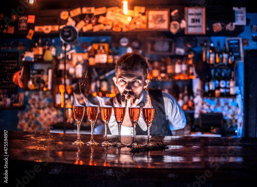 Confident barman demonstrates the process of making a cocktail at the night club