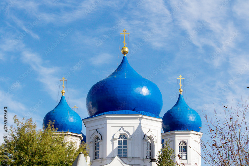 blue domes of an Orthodox church with a gold cross on a blue sky background