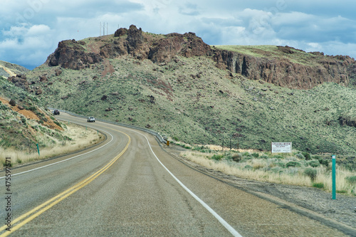 Empty U.S. 95 asphalt highway in Southern Idaho under a blue sky with large massive clouds photo