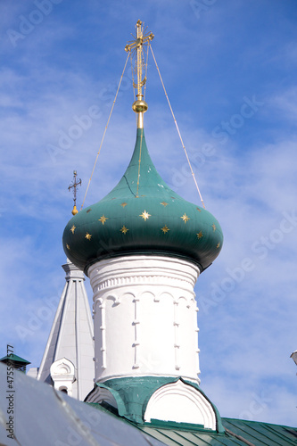 Green dome of a church with a gold cross and stars against the sky