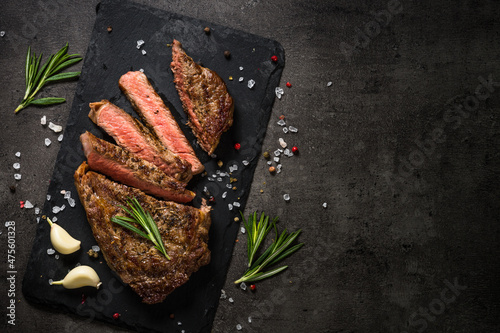 Grilled beef steak on black table.