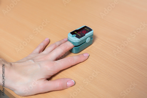 Close up shot of patient hand with pulse oximeter attached to finger for monitoring of saturation in the hospital photo
