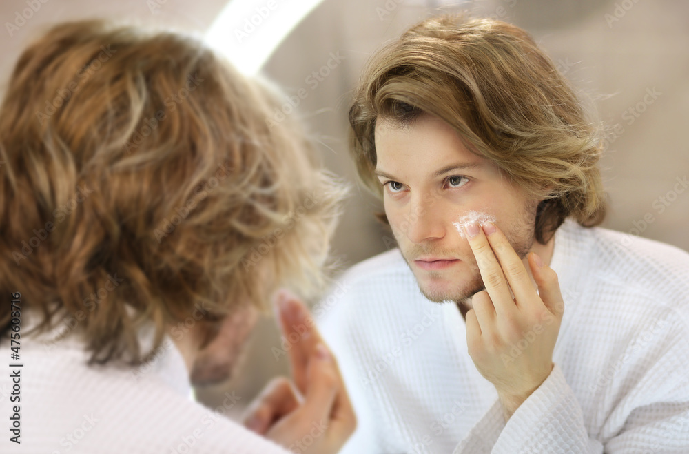 young man looking in the mirror,combing his hair,looking at problems on face young man looking in the mirror,combing his hair,looking at problems on face
