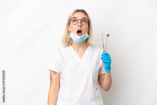 Dentist caucasian woman holding tools isolated on white background looking up and with surprised expression