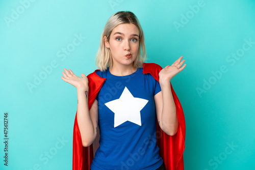 Super Hero caucasian woman isolated on blue background having doubts while raising hands