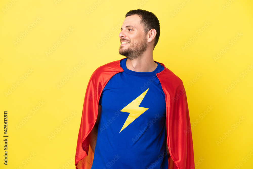 Super Hero Brazilian man isolated on yellow background looking side Super Hero Brazilian man isolated on yellow background looking side