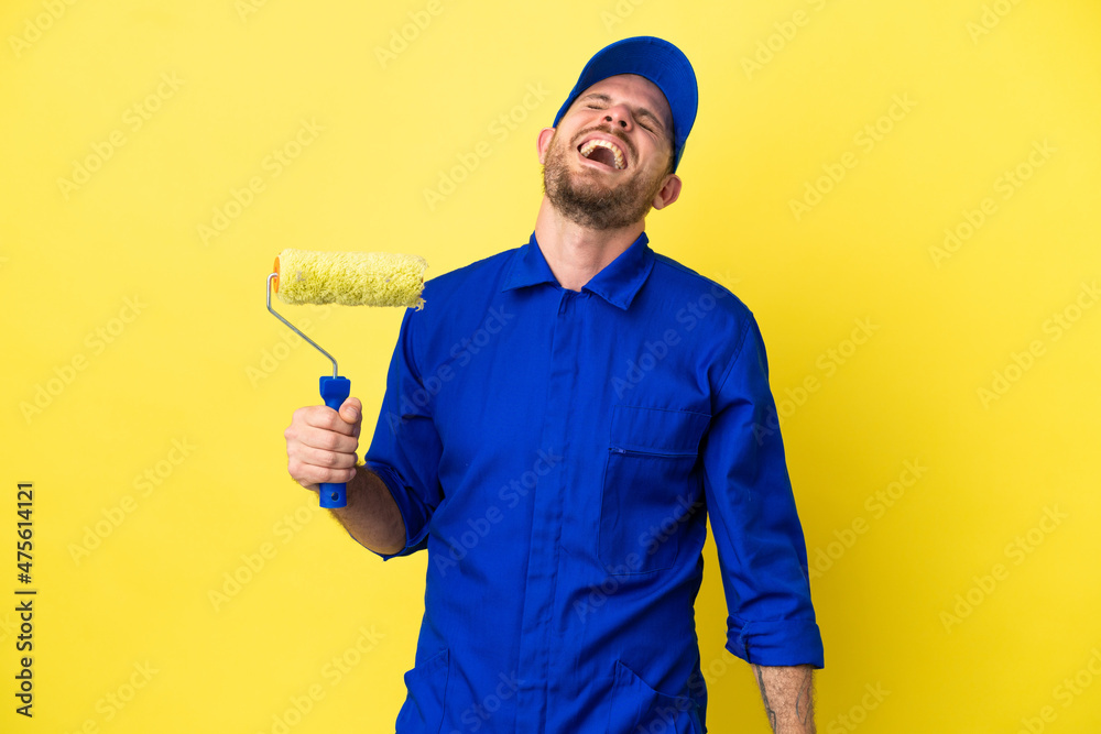 Painter Brazilian man isolated on yellow background laughing Painter Brazilian man isolated on yellow background laughing