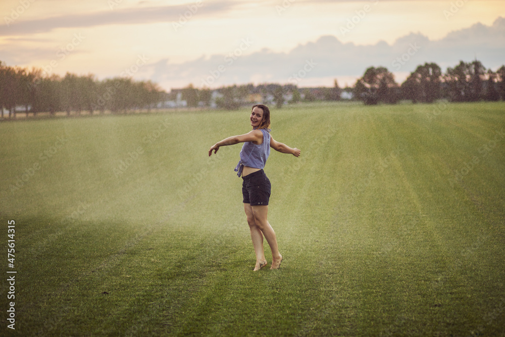 young woman having fun with water from a sprinkler. young woman having fun with water from a sprinkler.