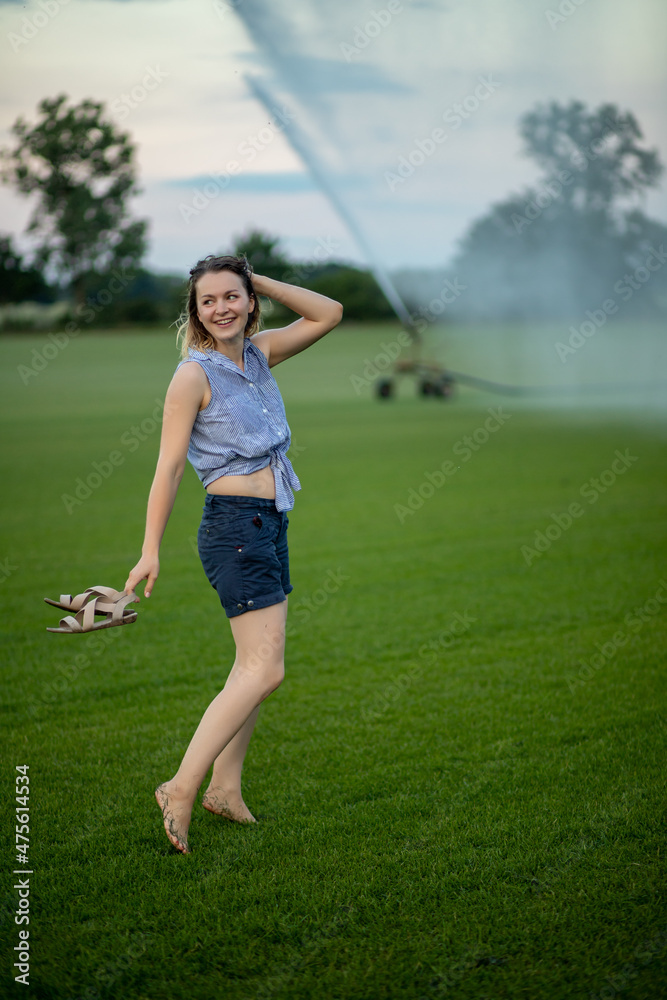 young woman having fun with water from a sprinkler. young woman having fun with water from a sprinkler.