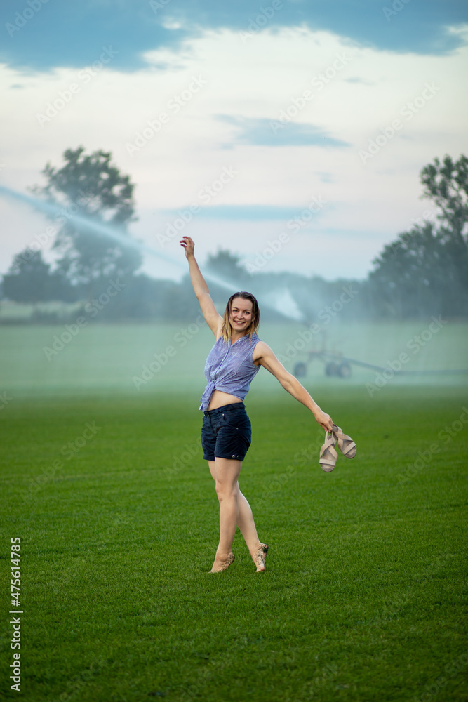 young woman having fun with water from a sprinkler. young woman having fun with water from a sprinkler.
