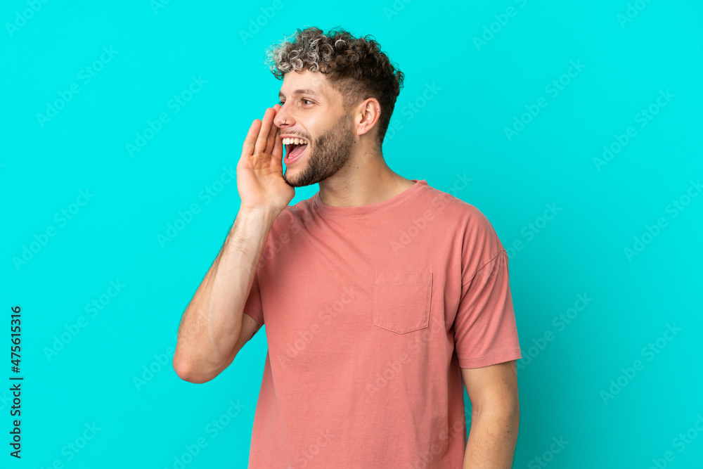 Young handsome caucasian man isolated on blue background shouting with mouth wide open to the side Young handsome caucasian man isolated on blue background shouting with mouth wide open to the side
