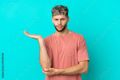 Young handsome caucasian man isolated on blue background having doubts