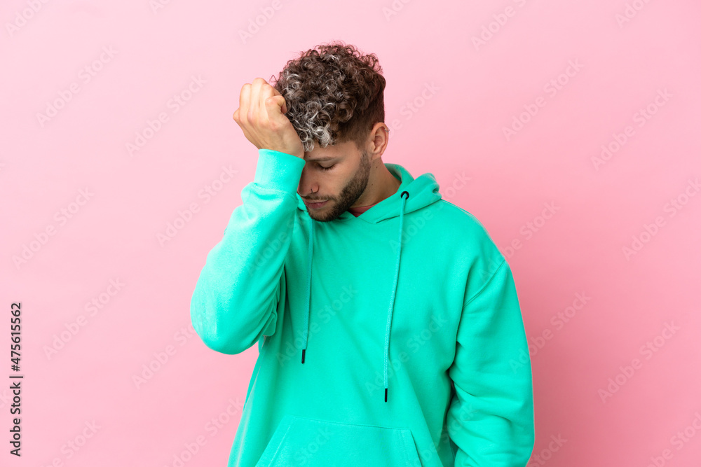 Young handsome caucasian man isolated on pink background with headache