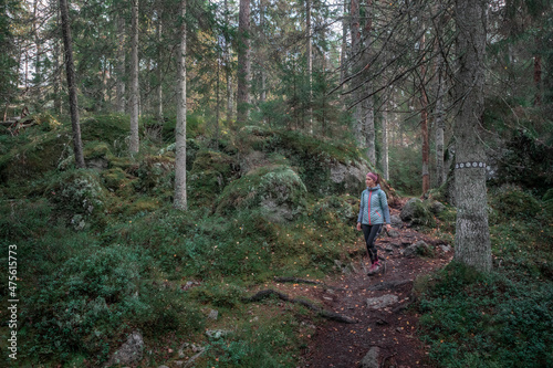 Woman hiking along footpath in the forest in Tiveden National Park in Sweden.