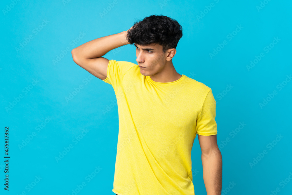 Young Argentinian man isolated on background having doubts while scratching head Young Argentinian man isolated on background having doubts while scratching head