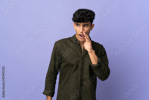 Young Argentinian man isolated on background whispering something with surprise gesture while looking to the side