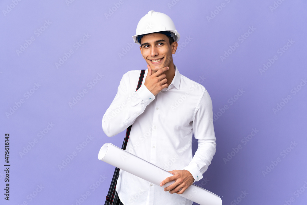 Young architect man isolated on background looking to the side and smiling Young architect man isolated on background looking to the side and smiling