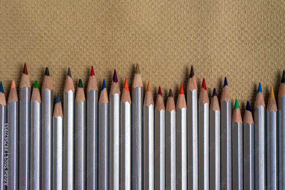 Row of colored pencils on embossed paper with copy space Row of colored pencils on embossed paper with copy space