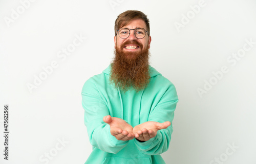 Young reddish caucasian man isolated on white background holding copyspace imaginary on the palm to insert an ad © luismolinero