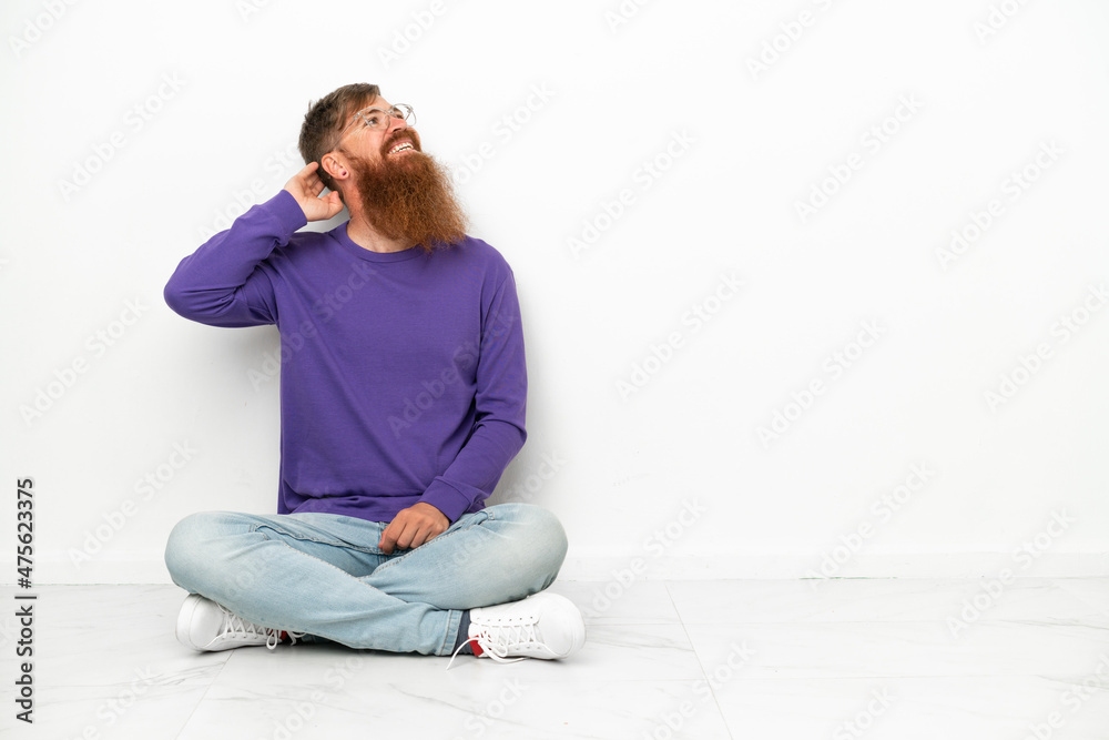 Young caucasian reddish man sitting on the floor isolated on white background thinking an idea