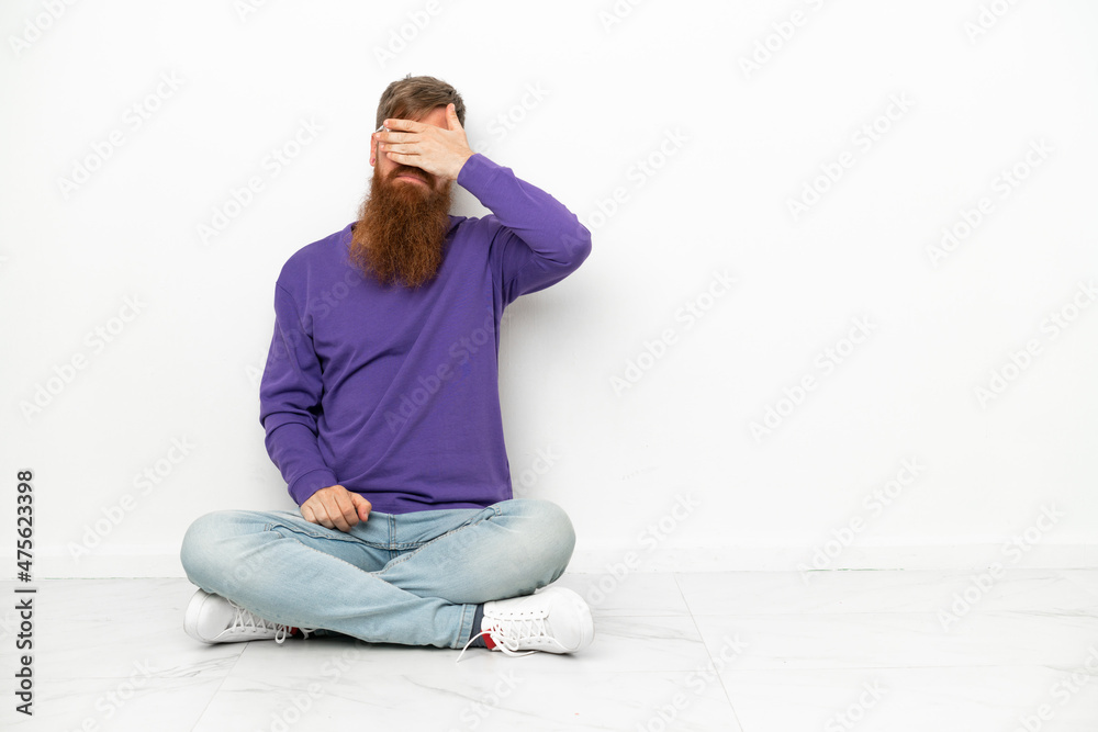 Young caucasian reddish man sitting on the floor isolated on white background covering eyes by hands. Do not want to see something Young caucasian reddish man sitting on the floor isolated on white background covering eyes by hands. Do not want to see something