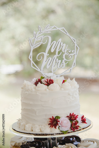 Silver Mr and Mrs Cake Topper on Small White Cake for Cutting with Red Flowers Outside in Natural Light