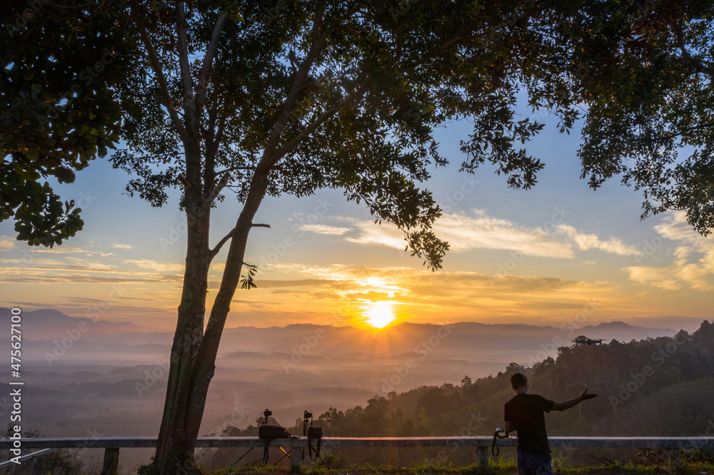 Obraz premium beautiful yellow sunrise at the horizon of mountain range in phang Nga Thailand..A pilot flying a drone to shooting view of the mist in the valley..beautiful sunrise in the mist background.