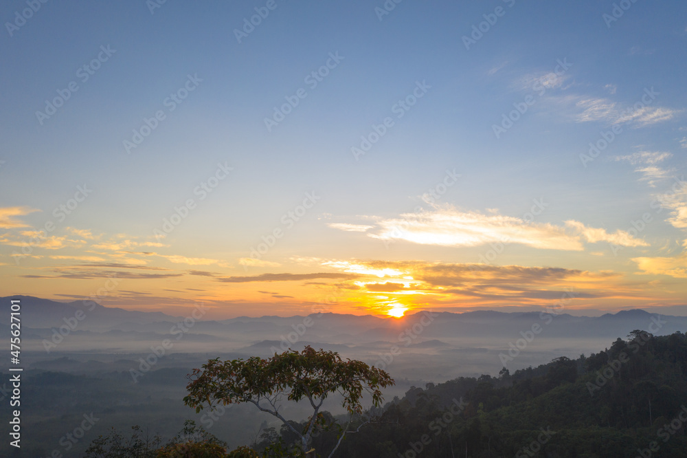 aerial view beautiful yellow sunrise above the mountain in phang Nga valley..slow floating fog blowing cover on the mountain look like as a sea of mist. .scenery golden sunrise at horizon background.
