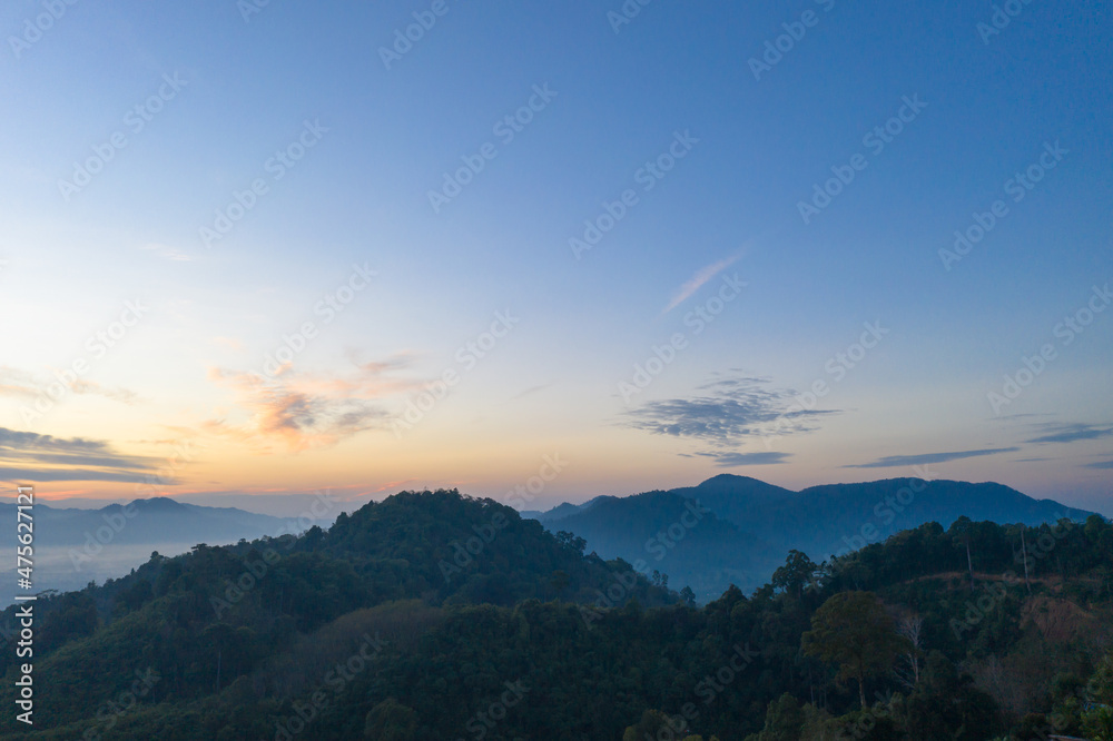 aerial view scenery sunrise above the mountain in tropical rainforest..slow floating fog blowing cover on the mountain look like as a sea of mist. .beautiful sunrise in the mist background.